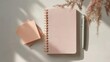 © CYBERPINK - Flat lay of a pink notebook with a spiral binding and a pen on the right side.