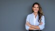 © PRO STOCK'S - A confident businesswoman with her arms crossed, smiling warmly against a plain grey background.