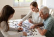 © Ievgen Skrypko - Grandpa And Granddaughters Work On A Puzzle Together, Different Generations Of A Family Spending Time Together
