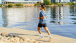© muse studio - Person jogging along the water at a city park