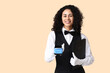 © Pixel-Shot - Young African-American waitress with payment terminal and menu on beige background