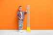 © New Africa - Little boy measuring his height with chart near orange wall