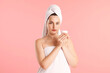 © New Africa - Beautiful woman with cream wrapped in towels against pink background