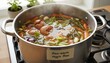 © Khaisan - Homemade Vegetable Broth Simmering Zero-Waste Cooking. Stock from Leftover Scraps. Stainless Pot on Gas Stove. Healthy Vegetarian Nutrition, Close-up