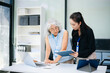 © laddawan - Asian senior and middle aged businesswomen working together in office, using smartphone and tablet
