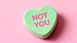 © Tania - Light green heart-shaped candy with 'not you' message on a pink background