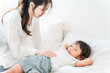 © buritora - Mother putting her daughter to sleep in bed (parenting, childcare)