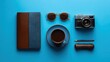 © Anat art - Luxurious Travel Setup on Blue Background With Coffee, Notebook, Camera, and Sunglasses for Adventure Preparation