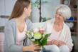 © auremar - woman visiting her grandmother and arranging flowers
