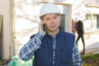 © auremar - builder at a building site talking on a mobile phone