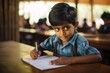 © nsit0108 - Indian schoolboy concentrating on writing in a notebook at his desk in school