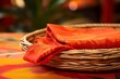 © nsit0108 - Orange patterned fabric folding inside a woven basket on a colorful tablecloth