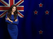 © millaf (Nemchinova) - Cheerful young woman in blue dress smiling against flag of New Zealand background