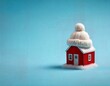 © NusratJahan - Miniature red house wearing white knitted hat on blue background for winter concept