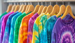 © wolfelarry - Row of tie dye shirts hang on wooden hangers. Colorful tshirts showcase dye sublimation. Vibrant apparel collection displays graphic
