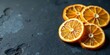 © wichit - Close-up of vibrant citrus fruit slices arranged on a dark textured surface