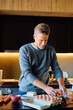 © we.bond.creations - Man smiling, preparing ingredients for a healthy breakfast in a modern kitchen. Cooking fresh food for balanced lifestyle