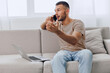 © SHOTPRIME STUDIO - Engaged man communicating on the phone, showing excitement and enthusiasm while sitting on a couch. Comfortable home office environment enhances productivity and connection.