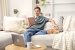 © New Africa - Smiling man reading book and stroking his cute cat on sofa at home