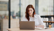 © David - Portrait of Young Successful Caucasian Businesswoman Sitting at Desk Working on Laptop Computer At The Office.