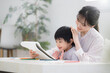 © kapinon - 母親（ママ）に見守られながら、ノートを開いて学びを楽しむ幼児　お絵描きや塗り絵など一緒に楽しむ 子どもを褒める母親　やり抜く力の非認知能力を育む
