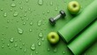 © Kristina - Top view of rolled green yoga mat, dumbbells, and apples on green surface with water drops for fitness and workout activities at home or gym