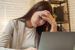 © Ekkasit A Siam - Asian businesswoman feeling exhausted resting head hand while using laptop evening office representing overwork fatigue burnout stress tired professional lifestyle modern corporate pressure