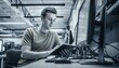 © Muhammad - Focused young man reading a book at a desk in a modern office with computers