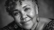 © MKS - In a monochrome portrait, a confident, mature African American woman with short natural hair smiles gently against a neutral gray background, radiating wisdom and authenticity