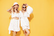 © halayalex - Two young beautiful smiling blond hipster female in trendy summer clothes. Blonde carefree women posing near yellow wall in studio. Positive models having fun. Cheerful and happy