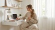 © Irina - Relaxed young woman with a peaceful mood writing in daily planner with coffee cup against a white minimalist home office background