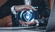 © ImageFlow - Businessman holding holographic padlock shield symbol, illustrating cybersecurity protection concept on futuristic interface background in office setting.