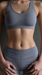 © pecherskiydotkz - Close-up of a toned midsection in gray athletic wear against a textured background, highlighting strength, fitness, and dedication to health.