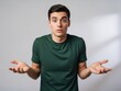 © PhotoHub - A young man with a puzzled expression on his face standing against a gray background with his hands outstretched in a questioning gesture