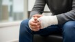© Sujabat - Person sitting with bandaged hand on their lap in a clinical setting