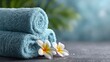 © tanawatbig - Soft Blue Towels with Frangipani Flowers on a Calm Background