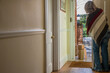 © Doodeez - A woman stands in the hallway and opens the front door after a home delivery drop off. A Parcel delivery man,courier has dropped off cardboard boxes and parcels direct to the front door of your house.