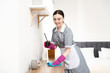 © New Africa - Woman with reed diffuser wiping dust from wooden cabinet indoors