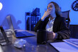 © New Africa - Sleepy woman with cup of drink yawning at workplace in office at night