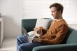 © New Africa - Smiling man with his cute cat using laptop on sofa at home. Space for text