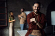 © Novak - Portrait of a confident professional man looking at the camera in a modern office, with diverse colleagues working in the blurred background.