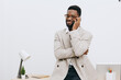 © SHOTPRIME STUDIO - Confident happy smiling African American man talking on mobile phone while standing at desk in modern office environment with white background and minimal decor, creating a professional and cheerful