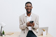 © SHOTPRIME STUDIO - Confident happy businessman standing at desk using smartphone, smiling, casual blazer, white shirt, modern workspace, clean background, lifestyle concept