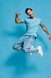 © SHOTPRIME STUDIO - Full body joyful happy energetic young man in light blue t-shirt jumps in the air with excitement, isolated on vibrant solid blue background. People lifestyle concept.