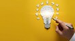 © starush - Light bulb puzzle on yellow background with hand placing final puzzle piece