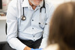 © Austockphoto - Young girl sitting on the examination bed looking at the male doctor