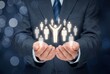 © Meow Creations - Businessman holding glowing human icons in hands representing human resources and leadership
