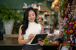 © Wasana - Florist woman checking orders on tablet in flower shop