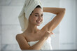 © fizkes - Care and confidence. Mirror reflection portrait smiling millennial girl wrapped in towels after morning bath procedures use solid perfumed antiperspirant on armpit to protect herself from sweat odor