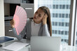 © fizkes - Too hot in office. Exhausted young woman employee wave paper fan at workplace struggle to work cope with migraine headache suffer from dry summer heat with broken air conditioner at overheated workday
